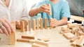 Boy pushing wooden block and starting domino effect. Wooden blocks falling in chain. Concept of children education at