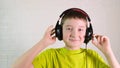 A boy put on headphones and listen to music, he shake and nod his head