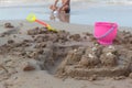 Boy put sand toys like pink plastic buckets, yellow and orange shovel. Used to build a sand castle Royalty Free Stock Photo