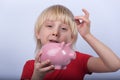 Boy puts coin into piggy Bank. Child learns to save money Royalty Free Stock Photo