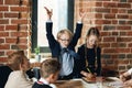 Boy with raised arms explaing the growth of business to colleagues