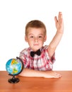 Boy raised his hand while sitting at table, near globe, isolated on white