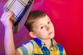 The boy raises a straw hat over his head in a sign of greeting and friendliness