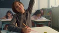 Boy raising hand during lesson at elementary school. Student writing in notebook Royalty Free Stock Photo