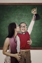 Boy raising trophy kiss by his mother in class Royalty Free Stock Photo