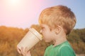 Boy in the rays of the sun in nature. He drinks from the eco-cup