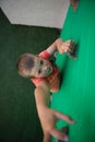 Boy reaching at climbing holds on green wall Royalty Free Stock Photo