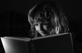 Boy reading bedtime story, dark room photo. Child reading a magic book in bed. Kid boy read books at home. Royalty Free Stock Photo