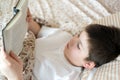 Boy reading book at bedtime lying in bed