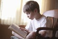 Boy Reading Book On Chair At Home Royalty Free Stock Photo