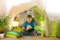 Reading and family games in children`s tent.  Boy with book  before going to bed Royalty Free Stock Photo