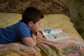 Boy reading a book lying on the bed Royalty Free Stock Photo