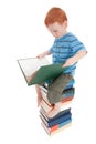 Boy reading kids book on pile of books