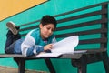 Boy reading and turning the page of a book lying on a bench Royalty Free Stock Photo