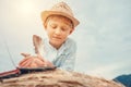 Boy reads a book lying on hay roll