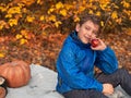 A boy with a red apple sits with autumn decoration and pumpkin Royalty Free Stock Photo