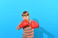 A boy in red boxing gloves makes an attacker punch