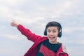 A boy in a red jacket and headphones smiling and shows his finger on the plane. Landing plane above sea waves in stormy weather Royalty Free Stock Photo