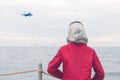 A boy in a red jacket looks at the sea waves in stormy rainy weather. Landing plane above sea waves in stormy rainy weather Royalty Free Stock Photo