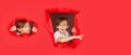 Boy in red paper hole pointing with finger aside. Surprised boy looking through hole in paper wall Royalty Free Stock Photo