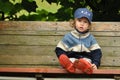 Boy in red rubber boots sitting on a rocking bench. Entangling Vines.