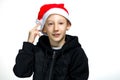 A boy in a red Santa hat holds his hand to his head and hits the hat Royalty Free Stock Photo