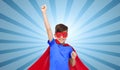 Boy in red super hero cape and mask showing fists