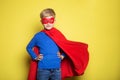 Boy in red super hero cape and mask. Superman. Studio portrait over yellow background Royalty Free Stock Photo