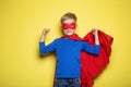 Boy in red super hero cape and mask. Superman. Studio portrait over yellow background Royalty Free Stock Photo