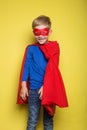 Boy in red super hero cape and mask. Superman. Studio portrait over yellow background Royalty Free Stock Photo