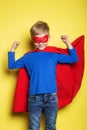 Boy in red super hero cape and mask. Superman. Studio portrait over yellow background Royalty Free Stock Photo