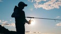 A boy is reeling up a fishing pole in sunlight