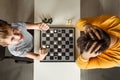 The boy rejoices in chess victory over his father. They play chess, family relationships, family. flat lay Royalty Free Stock Photo