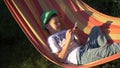 Boy relaxes in a hammock and using mobile phone