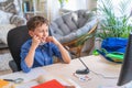 Boy removing a mask from his face while sitting at a computer, doing homework Royalty Free Stock Photo