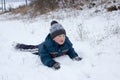 Boy resting in the snow,happy boy lies in the snow in winter with a rosy face