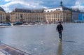 A boy rides a scooter on the Miroir d`eau in front of the Place de la Bourse in Bordeaux, France Royalty Free Stock Photo