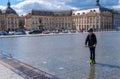 A boy rides a scooter on the Miroir d`eau in front of the Place de la Bourse in Bordeaux, France Royalty Free Stock Photo