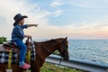 A boy riding horse with hand pointing and look out to the sea Royalty Free Stock Photo