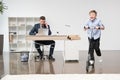 Boy riding skooter while his father working at office Royalty Free Stock Photo