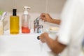 Boy rinsing toothbrush under running tap water in bathroom sink. Royalty Free Stock Photo