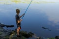 A boy with a rod in his hands on the river catching fish. Sport fishing on the river in summer Royalty Free Stock Photo