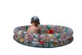 A boy in a round children`s pool on a white background in a cap. Royalty Free Stock Photo