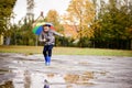 Boy in rubber blue rainboots jumping to dirty puddle