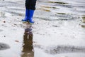 Boy in rubber blue rainboots jumping to dirty puddle Royalty Free Stock Photo