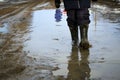 A boy in rubber boots walks through a puddle. Spring slush. Royalty Free Stock Photo