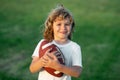 Boy with rugby ball. Cute child having fun and playing american football on green grass park. Royalty Free Stock Photo