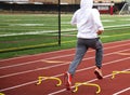 Boy running over small hurdles on a track outside in the cold