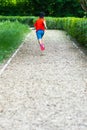 A boy running on the track surrounded by green bushes