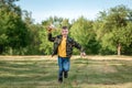 A boy runs across the field and launches a toy airplane against the backdrop of greenery. The concept of dreams, choice of Royalty Free Stock Photo